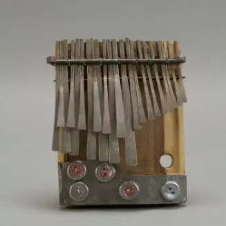 Close-up of a Zimbabwean mbira dzavadzimu thumb piano with metal keys on wood, and bottle caps attached for a buzzing resonance.