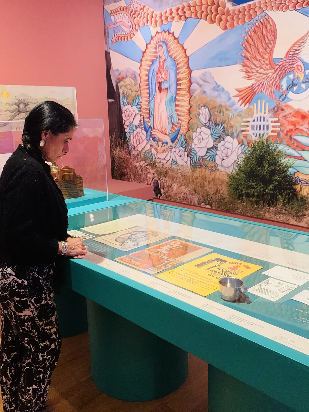 Woman viewing a museum exhibit case with Outta Joint concert flyers and artifacts