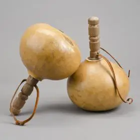 Two dried gourd rattles with carved wooden handles and looped leather cord, joined together to form a musical instrument.