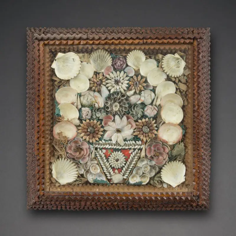 Framed folk sailor's valentine with shells arranged into flower and geometric patterns, set in a chip-carved wooden frame.