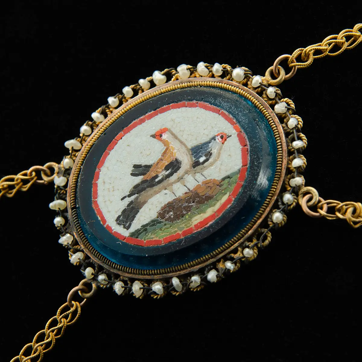 Close-up of gold necklace medallion with mosaic of two doves on twisted gold chain links