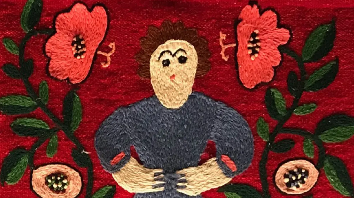 A decorative textile rug featuring a central figure in a blue top with hands on their waist, surrounded by large pink flowers and green leaves on a red background.