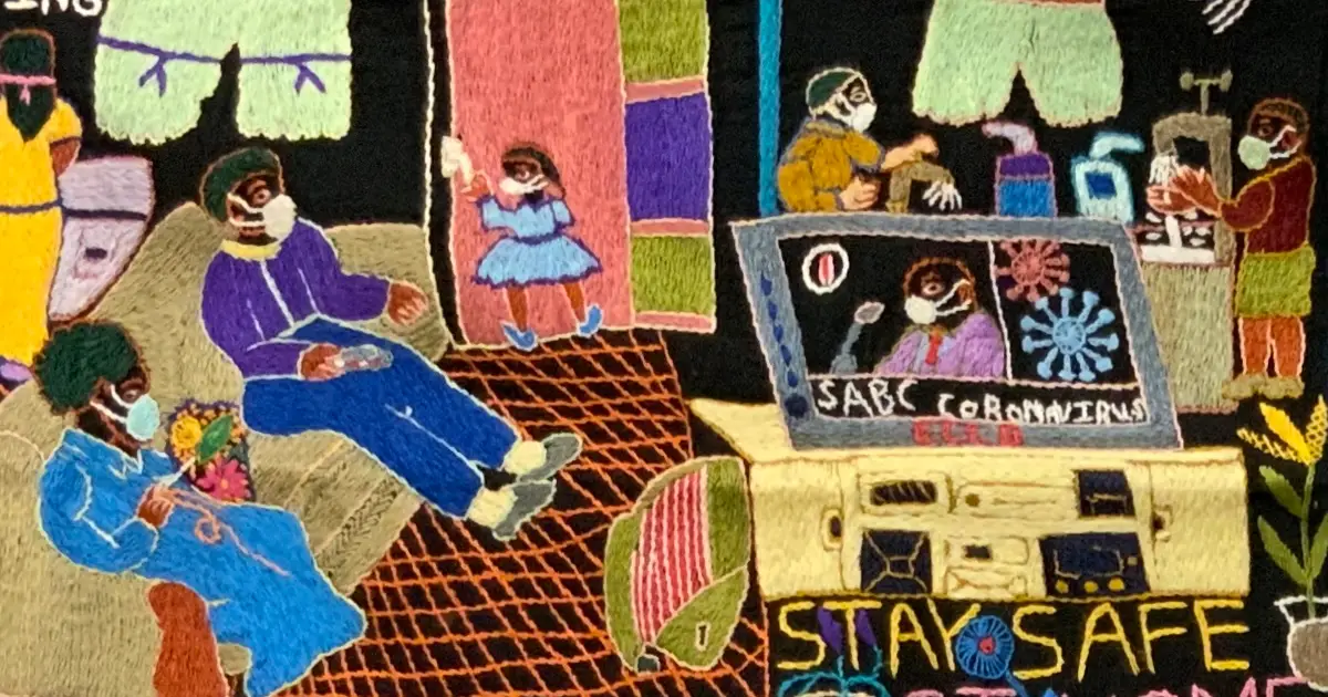 Colorful embroidery street scene of life during COVID with several masked people sitting and walking near a yellow bus displaying the phrase “STAY SAFE.”